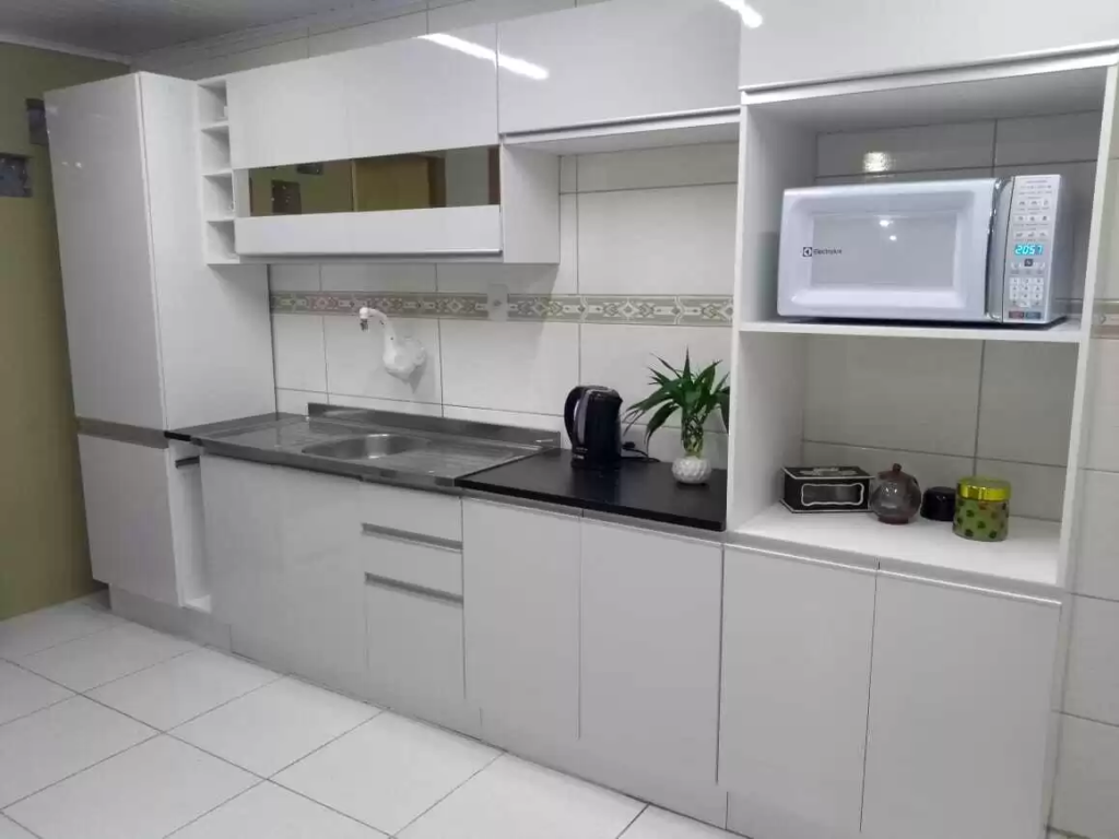 Cozinha Madesa da linha Acordes, na cor branca, decorada na estética clean e minimalista com poucos itens e eletrodomésticos.