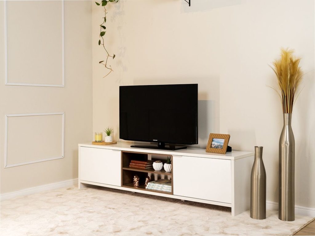 Sala de estar com as paredes pintadas de bege e detalhes em branco. Rack Madesa na cor branca, TV e diversos objetos decorativos. 