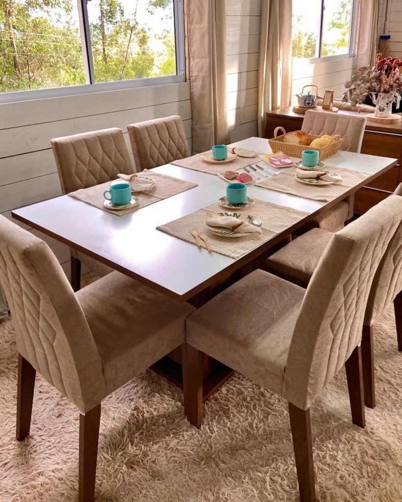 Conjunto de sala de jantar Madesa, nas cores crema e rustic, com a mesa posta e decorada e um tapete bege.
