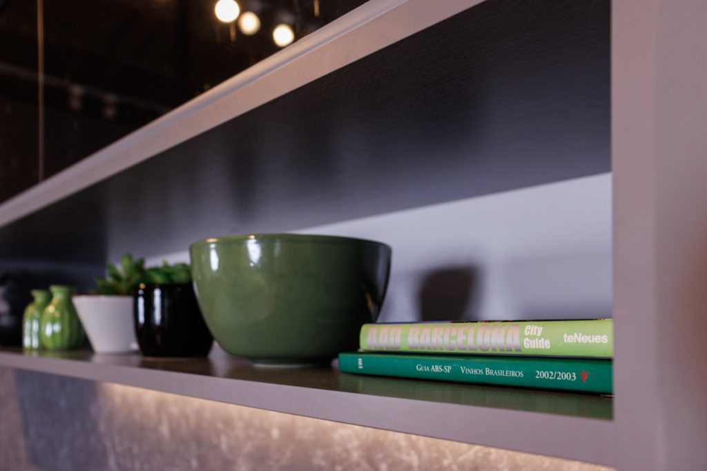 Prateleira de cozinha Madesa, na cor cinza, decorada com diversos vasos de planta e livros em tons de verde.