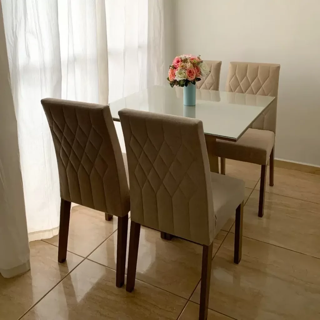 Conjunto de sala de jantar Madesa com 4 cadeiras na cor crema, decorado com um arranjo de flores brancas e rosas.