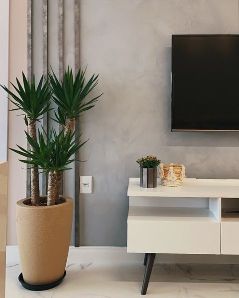 Sala de estar, decorada com rack Madesa na cor branca e um vaso de plantas grande, à esquerda.