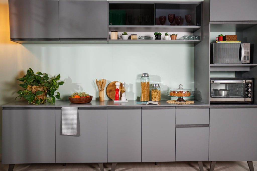 Cozinha Nice Madesa, na cor cinza, decorada com diversos utensílios e eletrodomésticos nos nichos à direita.