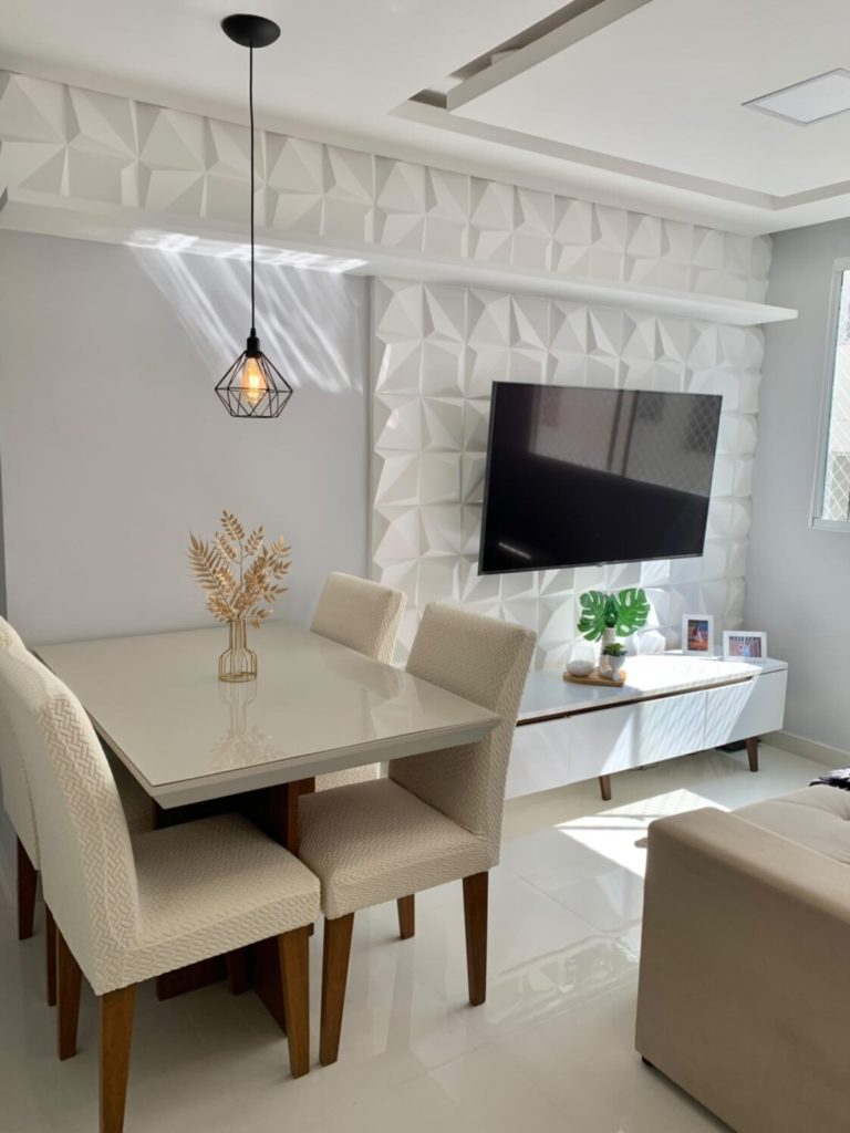 uma sala de estar em tonalidades claras está decorada com o rack Madesa Reims Branco, mesa e cadeiras em tons creme e objetos decorativos em formato de folhas verdes.