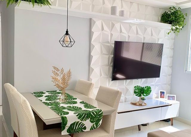 uma sala de estar em tonalidades claras está decorada com o rack Madesa Reims Branco, mesa e cadeiras em tons creme e objetos decorativos em formato de folhas verdes.