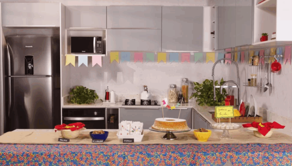 Cozinha decorada com bandeirinhas de festa junina, com comidas típicas na bancada.