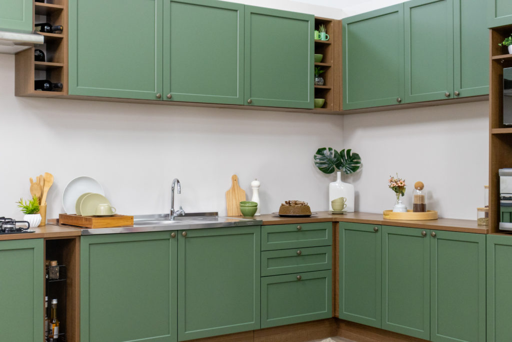 Armário de cozinha da linha Vik. Cozinha com portas verde floresta com caixaria em amadeirado rústico escuro em frente a uma paree clara.