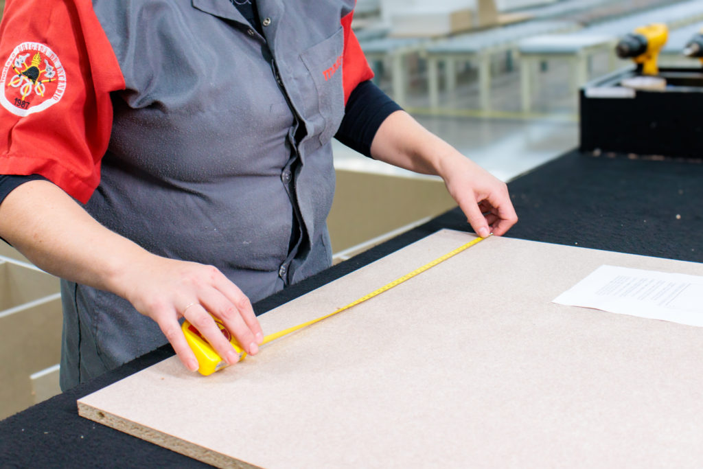 Colaboradora Madesa medindo uma peça de MDF.
