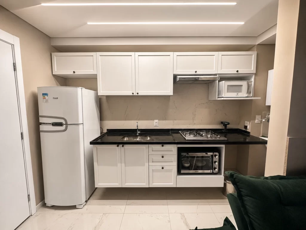 Cozinha compacta branca linha Vik organizada, com bancada e armários que facilitam a limpeza