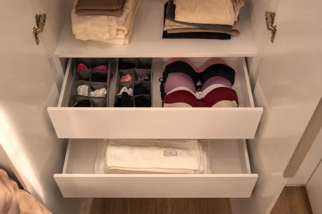 Gavetas de guarda-roupa com organizadores com divisórias para peças íntimas e roupas dobradas por categoria.