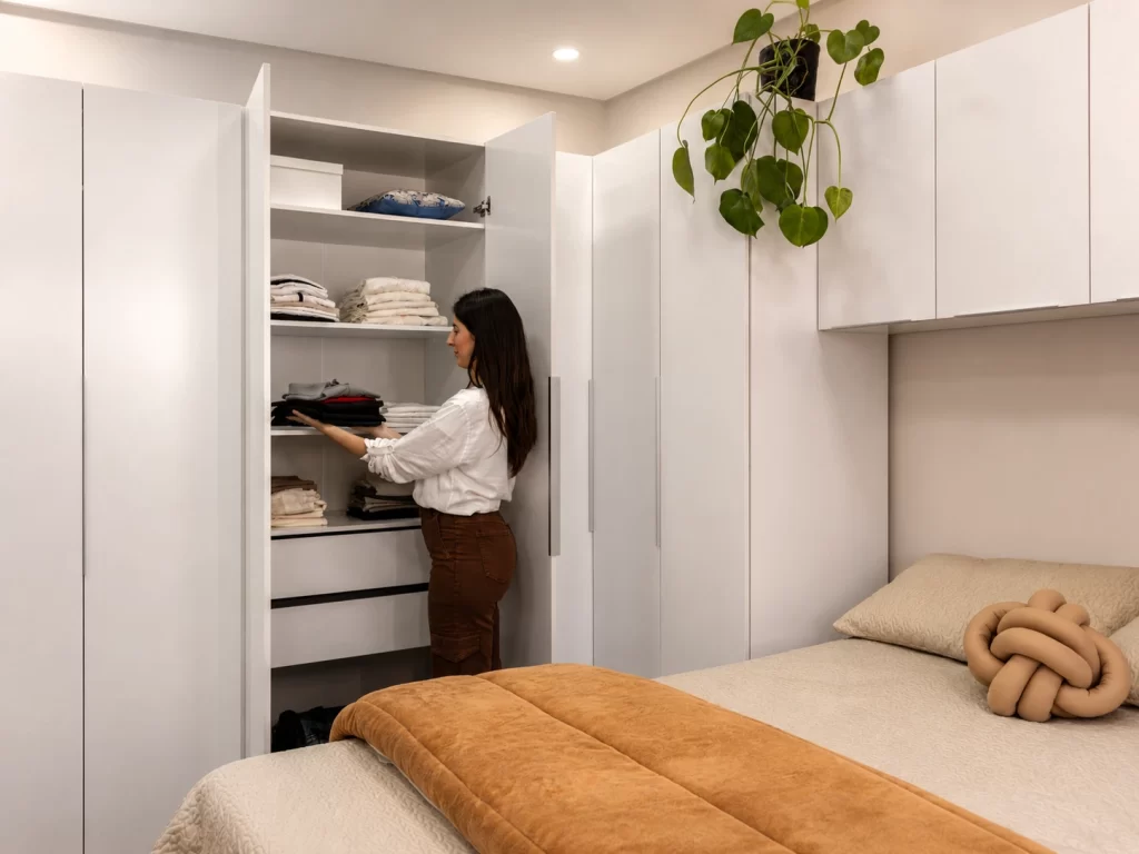 Guarda-roupa modulado branco linha NEO da Madesa em quarto de apartamento, com prateleiras e gavetas internas.