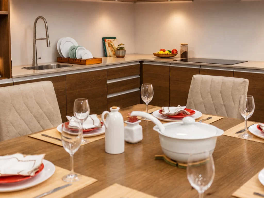 Mesa de jantar amadeirada com cadeiras estofadas da Madesa posta, integrada à cozinha de um apartamento.