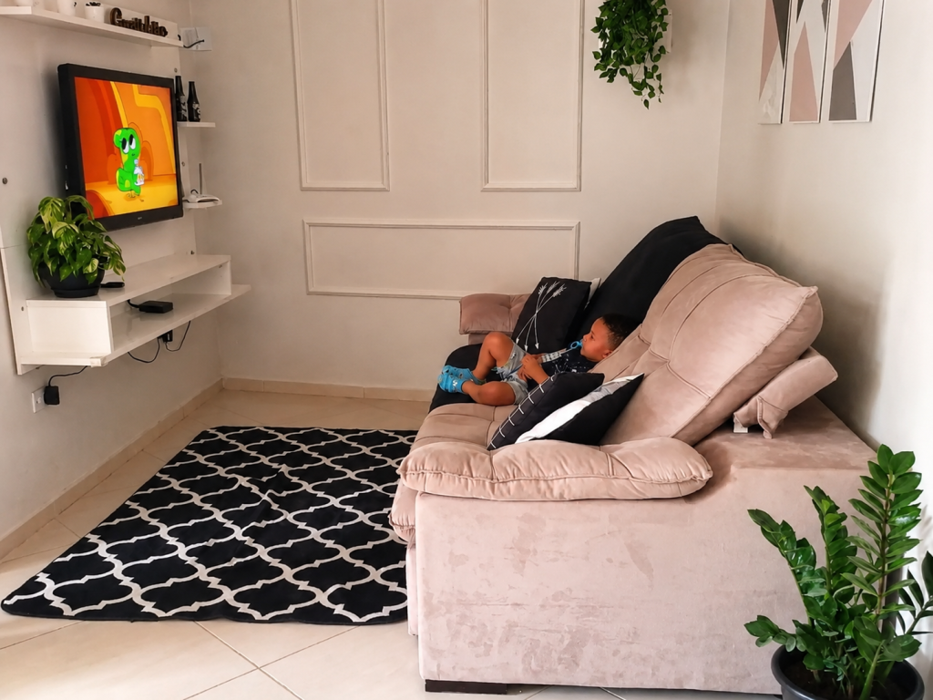 Sala de estar com painel branco para TV da Madesa e sofá, ambiente de convivência de um apartamento.