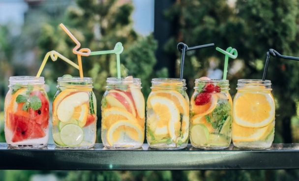 A imagem mostra seis canecas de vidro com bebidas e frutas, exemplificando o home bar.