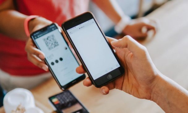 Cliente apontando a câmera do celular para QR Code gerado pela vendedora para pagar sua compra.