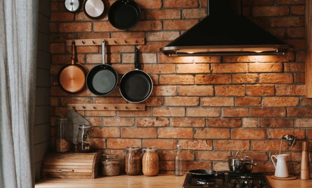 Cozinha estilo industrial decorada com parede em tijolinho aparente, elétros pretos e detalhes em madeira.