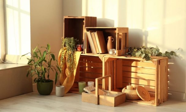 Estante feita com caixotes de feira e decorada com plantas para exemplificar o uso de móveis usados no design sustentável.