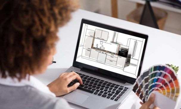 Mulher criando um projeto de cozinha modulada no computador e escolhendo tons em uma paleta de cores.