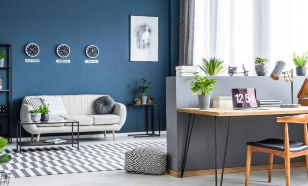 Sala com paredes azul e sofá branco com um canto para home office.