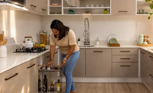 Mulher usando um módulo aramado extraível em cozinha planejada crema linha Agata da Madesa em apartamento.
