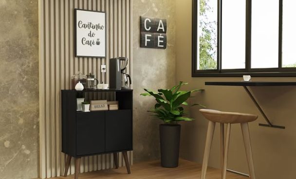 Cantinho de café decorado com uma parede de fundo com revestimento de ripas de madeira e uma parede de textura dourada, um móvel preto com máquina de café, xícaras e potes, uma placa com a frase "Cantinho do café", uma planta em vaso preto ao lado, uma janela grande com moldura preta e uma pequena mesa de madeira com um banquinho ao lado.