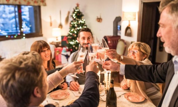 A imagem mostra pessoas reunidas à mesa celebrando uma ceia de ano novo simples e barata