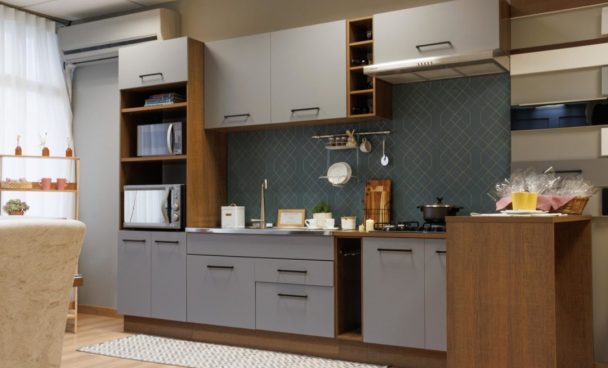 A imagem ilustra um projeto de cozinha Madesa na cor cinza com puxadores pretos e bancadas decoradas com utensílios de cozinha e eletrodomésticos.