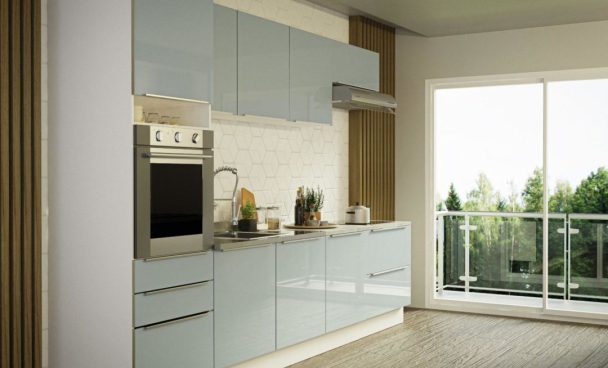 : cozinha madesa com armários claros em cozinha unilateral, à direita está uma varanda com vidros e grade de vidro.