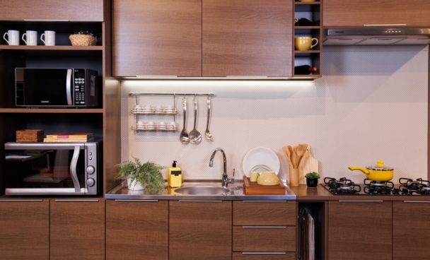 Cozinha Stella, na cor Rustic, decorada com eletrodomésticos e utensílios de cozinha na cor amarela.