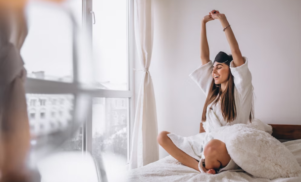 A imagem ilustra uma jovem mulher acordando em seu quarto branco após fazer a higiene do sono.