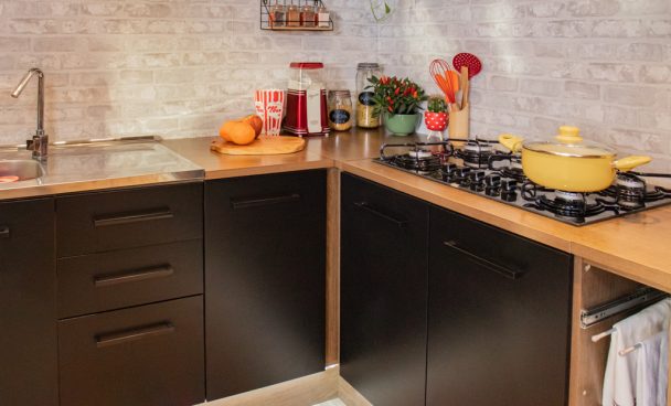 Bancada da cozinha Agata, nas cores preto e rustic, decorada com louças, vasos e outros utensílios coloridos.