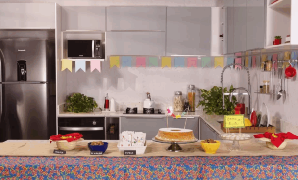 Cozinha decorada com bandeirinhas de festa junina, com comidas típicas na bancada.