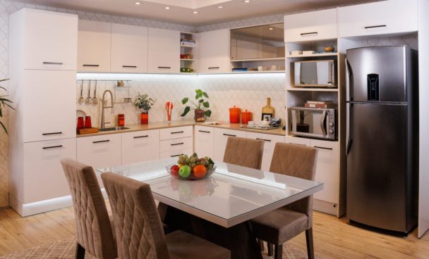 Cozinha Ágata Madesa na cor branca, com decoração e uma mesa de jantar ao centro.