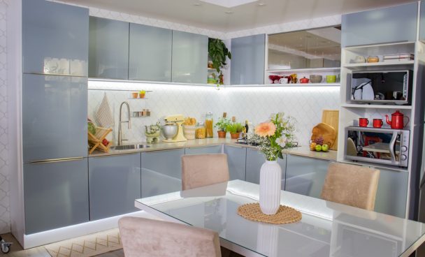 A imagem ilustra uma cozinha planejada em l na cor cinza e uma mesa de jantar de quatro lugares à sua frente.