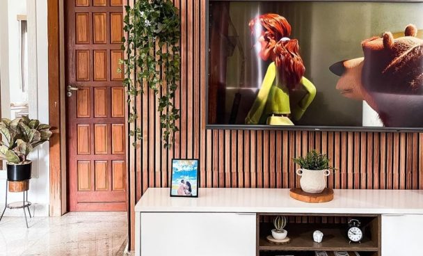 A imagem mostra um hack branco, plantas e uma tv logo acima, simbolizando uma sala de estar moderna.