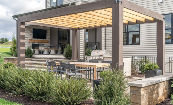 na imagem, um deck com churrasqueira na área externa de uma casa, com plantas e uma claraboia.