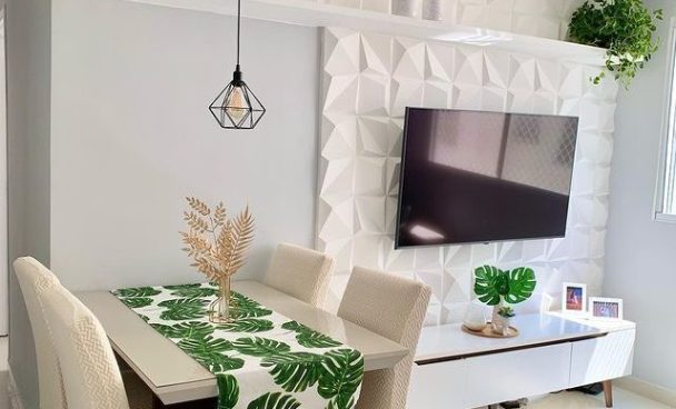 uma sala de estar em tonalidades claras está decorada com o rack Madesa Reims Branco, mesa e cadeiras em tons creme e objetos decorativos em formato de folhas verdes.