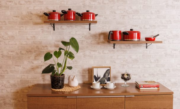 Aparador e prateleiras Madesa, na cor rustic, decorados com panelas, quadros, plantas e livros.