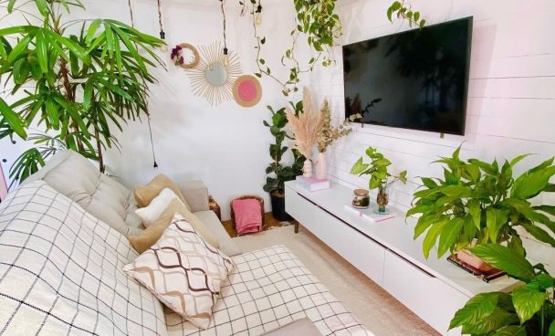Sala de estar com rack Madesa, decorada com diversas plantas, tecidos estampados no sofá e decorações naturais.