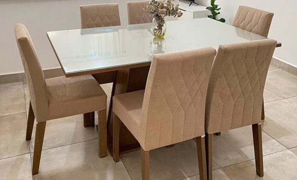 Mesa de jantar Rafaela Madesa, com tampo de vidro e cadeiras nas cores crema e rustic, decorada com um vaso no centro.