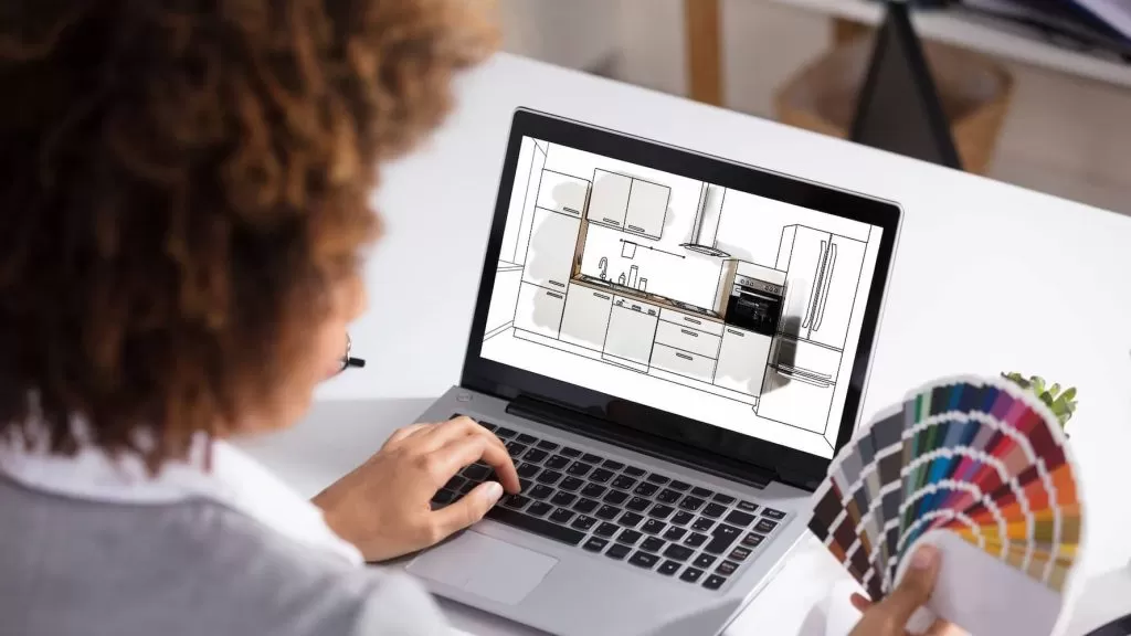 Mulher criando um projeto de cozinha modulada no computador e escolhendo tons em uma paleta de cores.