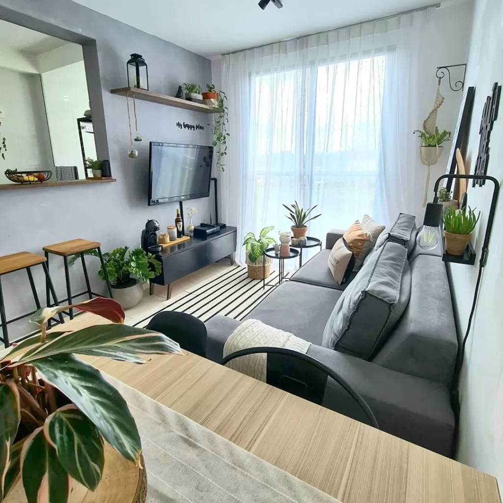 Sala de apartamento pequeno decorada com sofá, rack Madesa Reims e plantas.