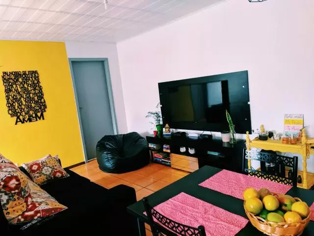 Sala de cliente Madesa com paredes rosas e amarelas e móveis pretos, um exemplo claro de como combinar cores complementares.