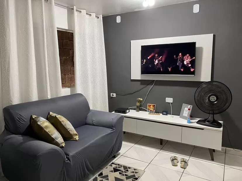 Sala com paredes cinzas e brancas e rack e painel Madesa na cor branca, como exemplo da combinação entre o branco, o cinza e o preto.