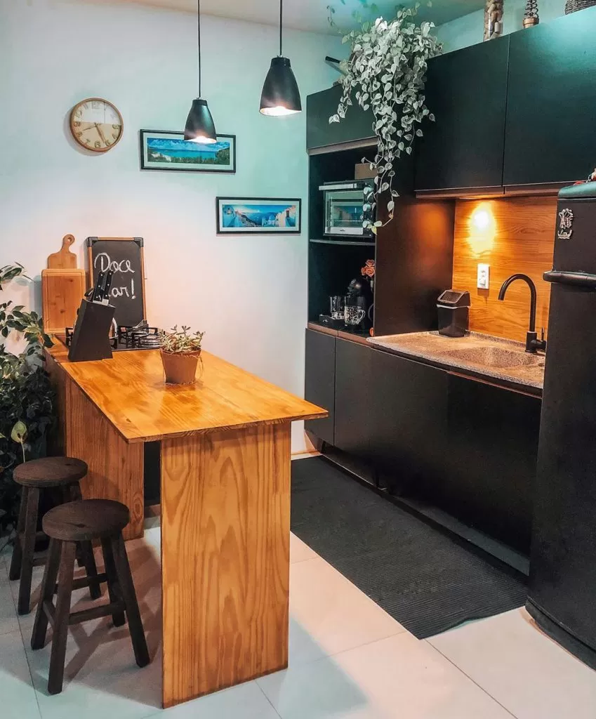 Cozinha com móveis pretos e com detalhes em madeira, que combinam muito com o estilo industrial.