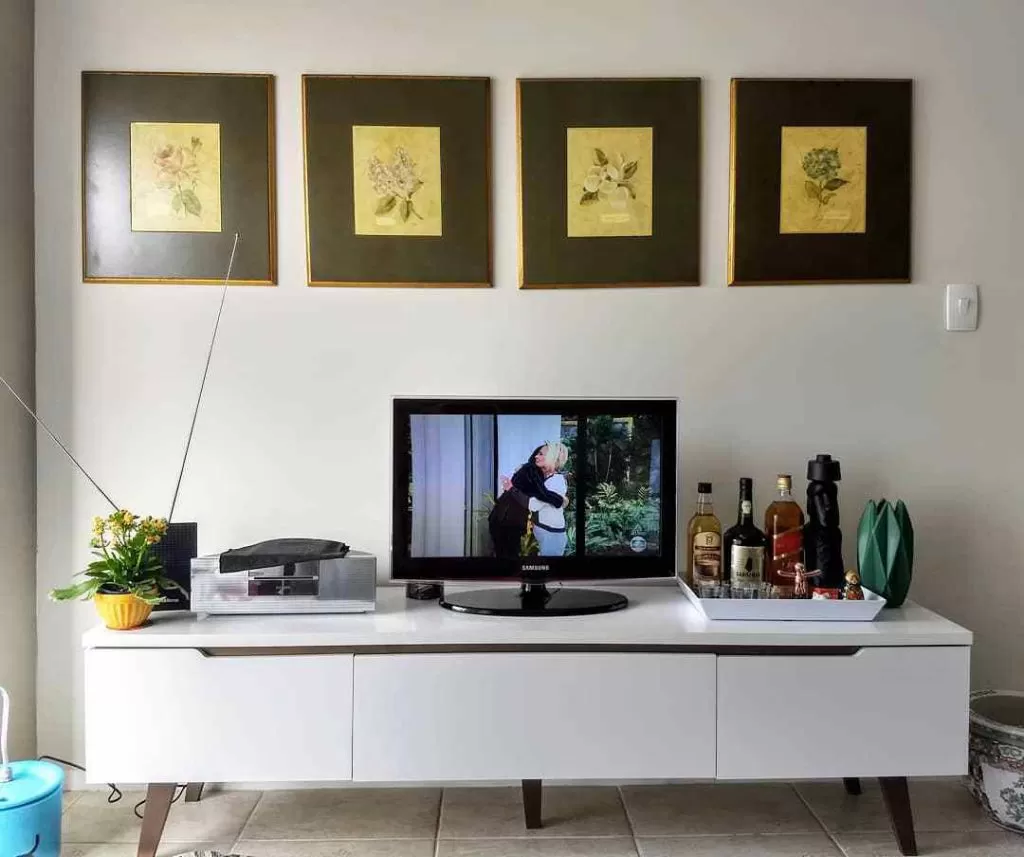 Sala de cliente Madesa decorada com rack Reims branco e quadros na parede.