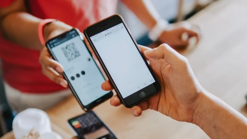 Cliente apontando a câmera do celular para QR Code gerado pela vendedora para pagar sua compra.
