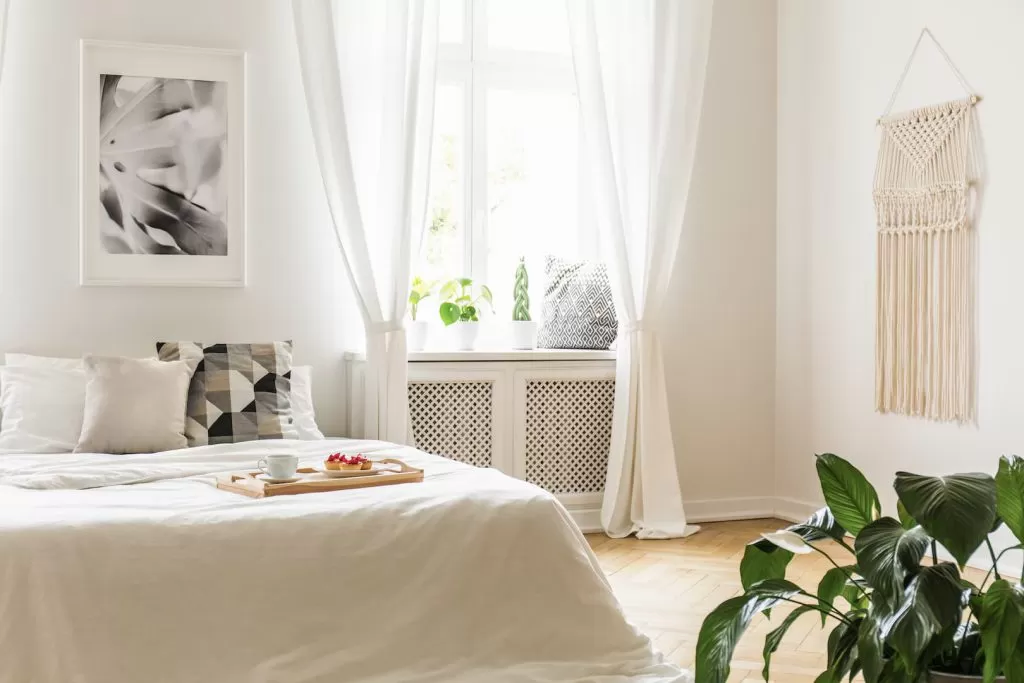Quarto decorado em tons de branco com ótima entrada de iluminação natural.
