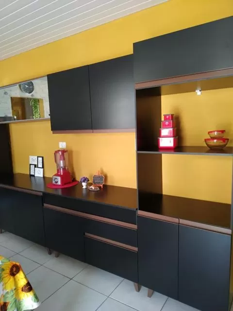 Cozinha Madesa Reims preta em um ambiente pintado de amarelo, uma escolha ousada que dá certo quando pensamos em como pintar a parede.