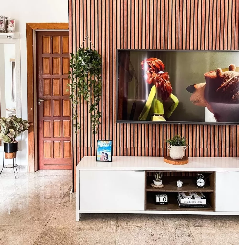A imagem mostra um hack branco, plantas e uma tv logo acima, simbolizando uma sala de estar moderna.